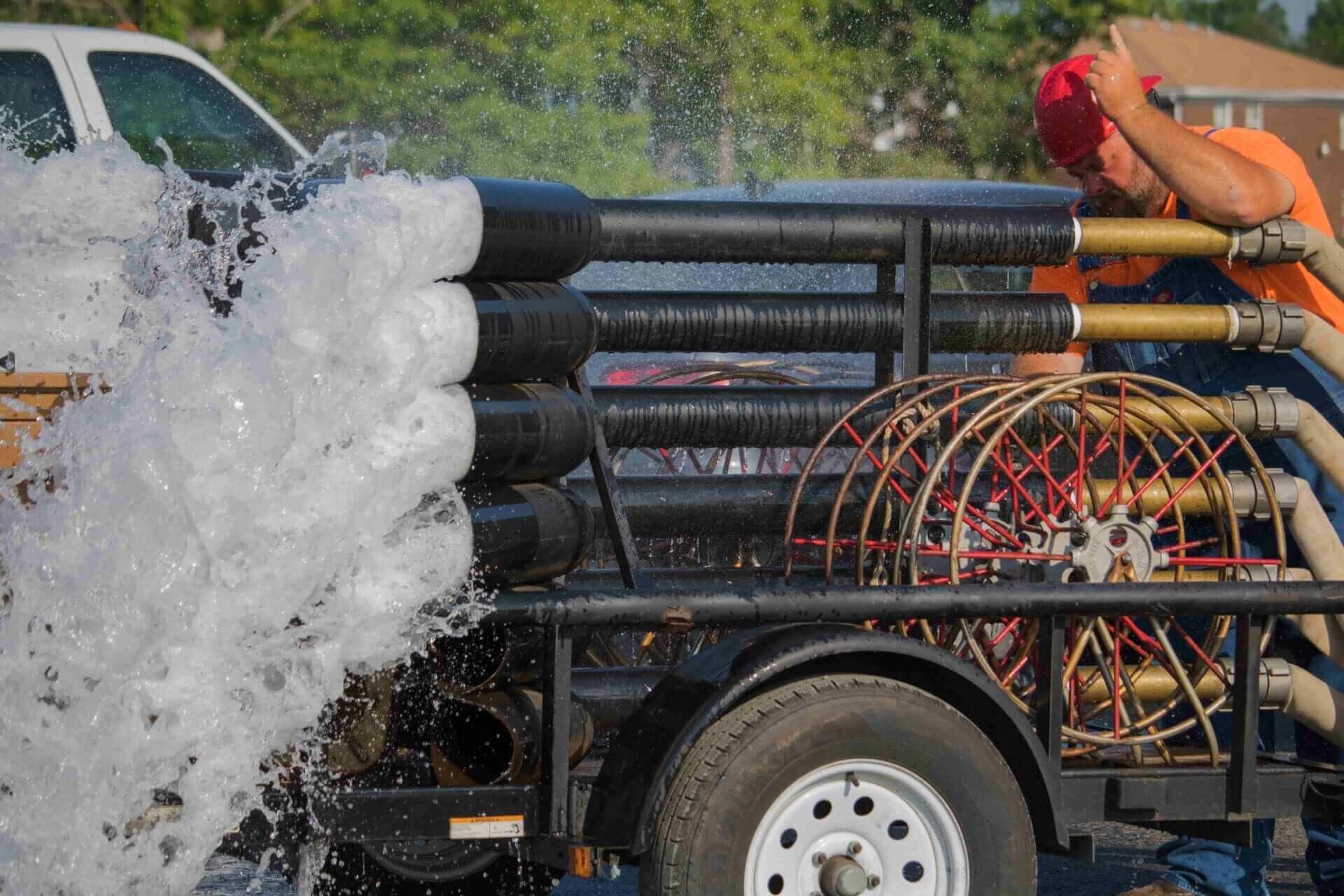 Water spraying our of hoses connected to a Midwest Sprinkler truck